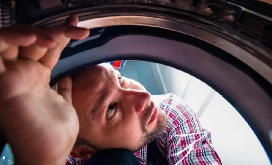 A repair man investigate washing machine grinding noise